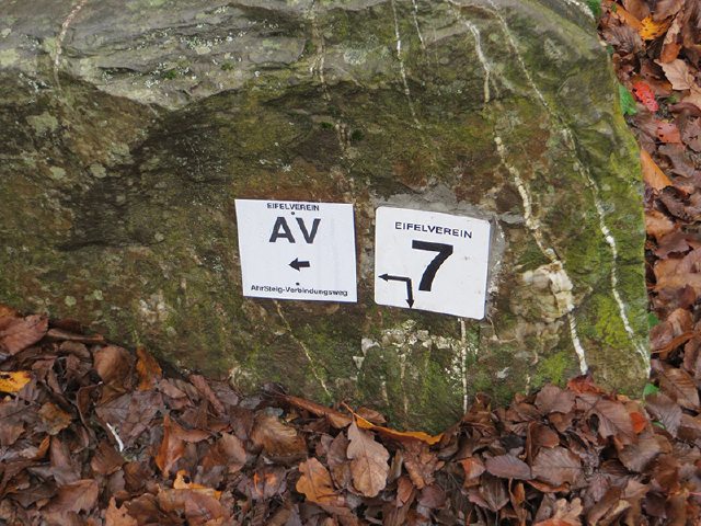 Wegmarkierungen AV und 7 an einer Sitzbank: Gehört der Vergangenheit an: der alte AV ist nun offiziell zur 5. Etappe des AhrSteigs gekürt worden (Foto: Hans-Joachim Schneider)