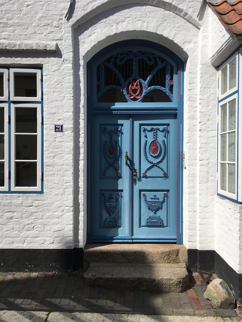Blaue Haustür mit roten und dunkelblauen Zierelementen: das macht die Schönheit der Altstadt Husums aus