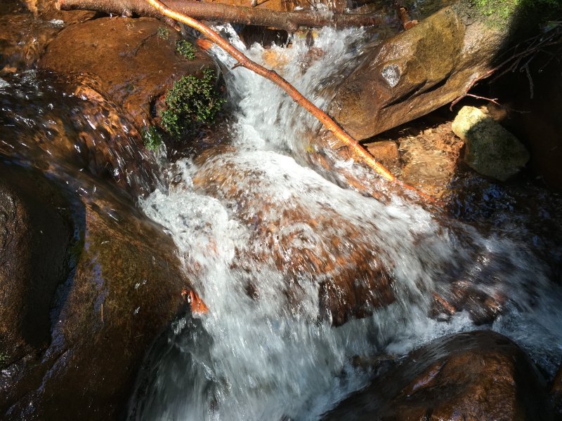 Ein kleiner Wasserfall, wasser das perlend über Steine springt