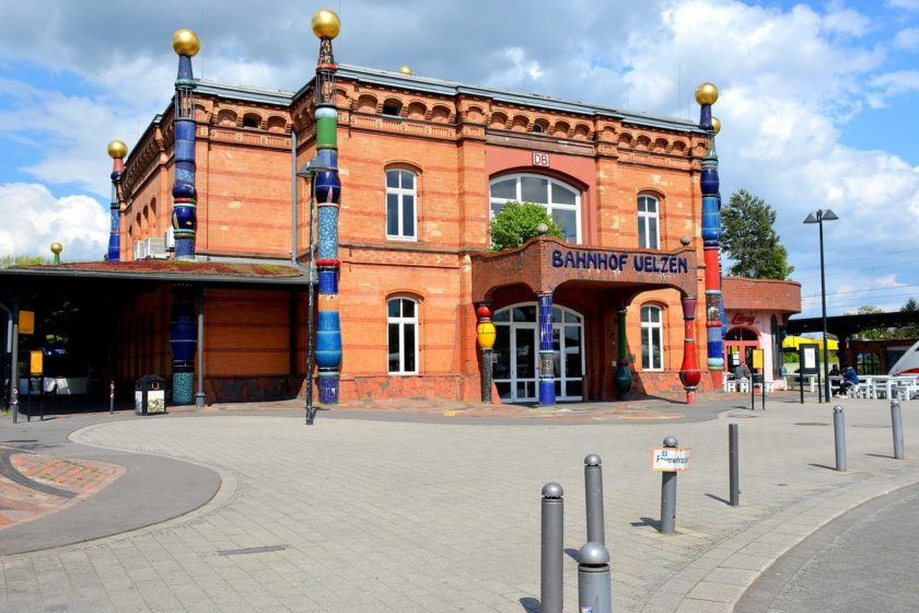 Rötliches Bahnhofsgebäude mit bunten Verzierungen, gestaltet von Friedensreich Hundertwasser
