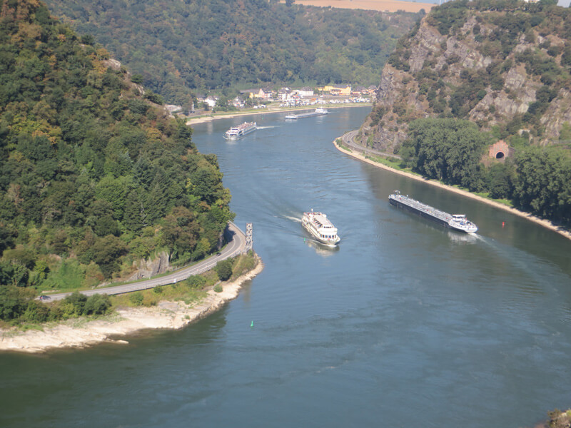 Blick von oben auf den großen Fluss, den Rhein, links und rechts schroffe Hänge, der rechte ist der berühmte Loreleyfelsen. In dieser engen Flussschleife sind früher viele Schiffe verunglückt. 